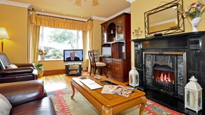 A living room with a fireplace, leather sofa, wooden coffee table, and a television. - Atlantic View (Galway)