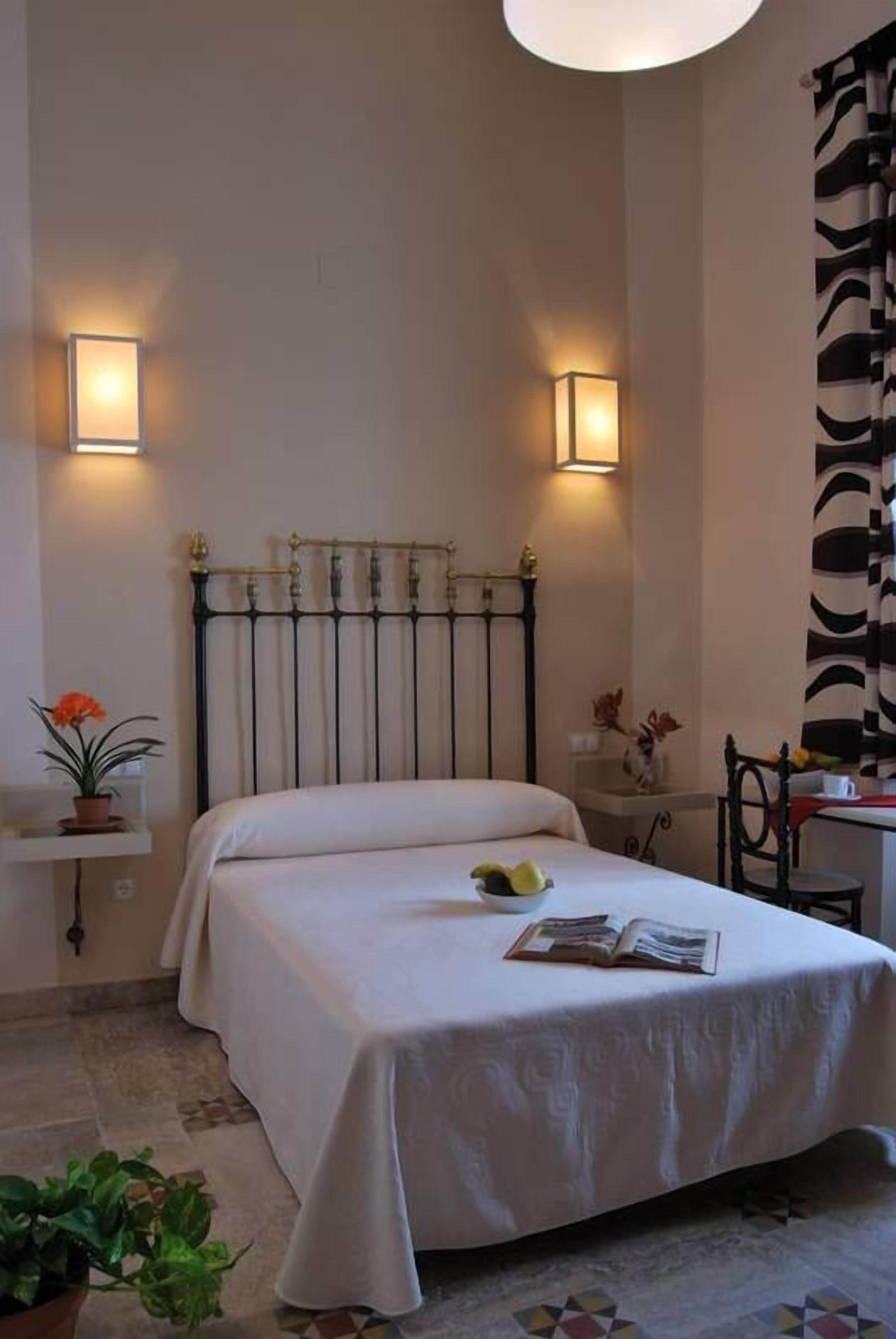 A neatly arranged bedroom with a bed, bedside tables, and wall-mounted lamps.