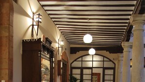 A hallway with patterned floor tiles, a wooden cabinet with glass doors, and a potted plant. - Hotel Rural Casa Grande Almagro (Almagro)