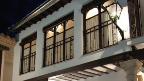 A two-story building with a covered patio area featuring wicker chairs, a glass table, and potted plants. - Hotel Rural Casa Grande Almagro (Almagro)