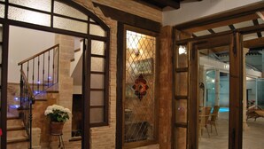 A staircase with a wooden railing, a potted plant, and a decorative glass window. - Hotel Rural Casa Grande Almagro (Almagro)