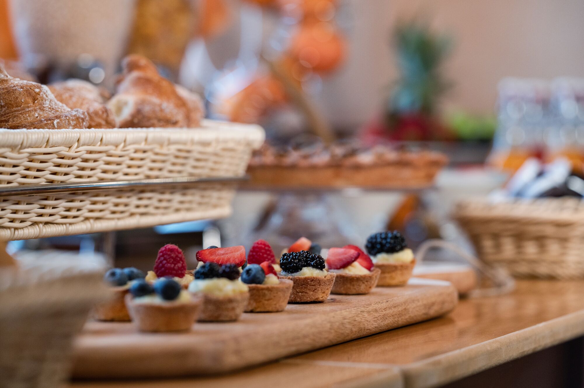 Un bufé con diversas opciones de comida, incluyendo pasteles y tartaletas de fruta.