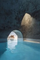 Una piscina interior con una silla de descanso bajo una estructura arqueada grande.