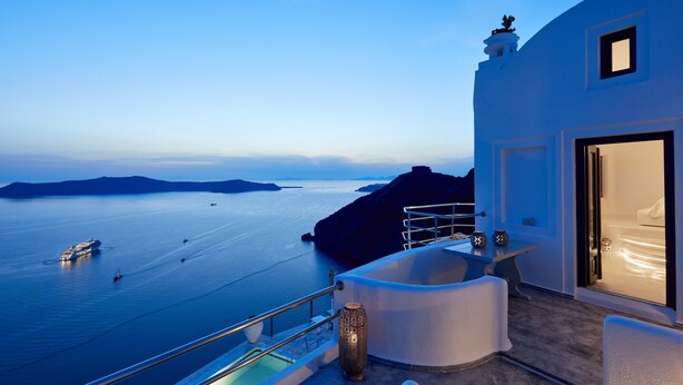 A modern hotel with a balcony overlooking a calm sea, a pool, and a view of distant islands. - Homeric Poems (Santorini)