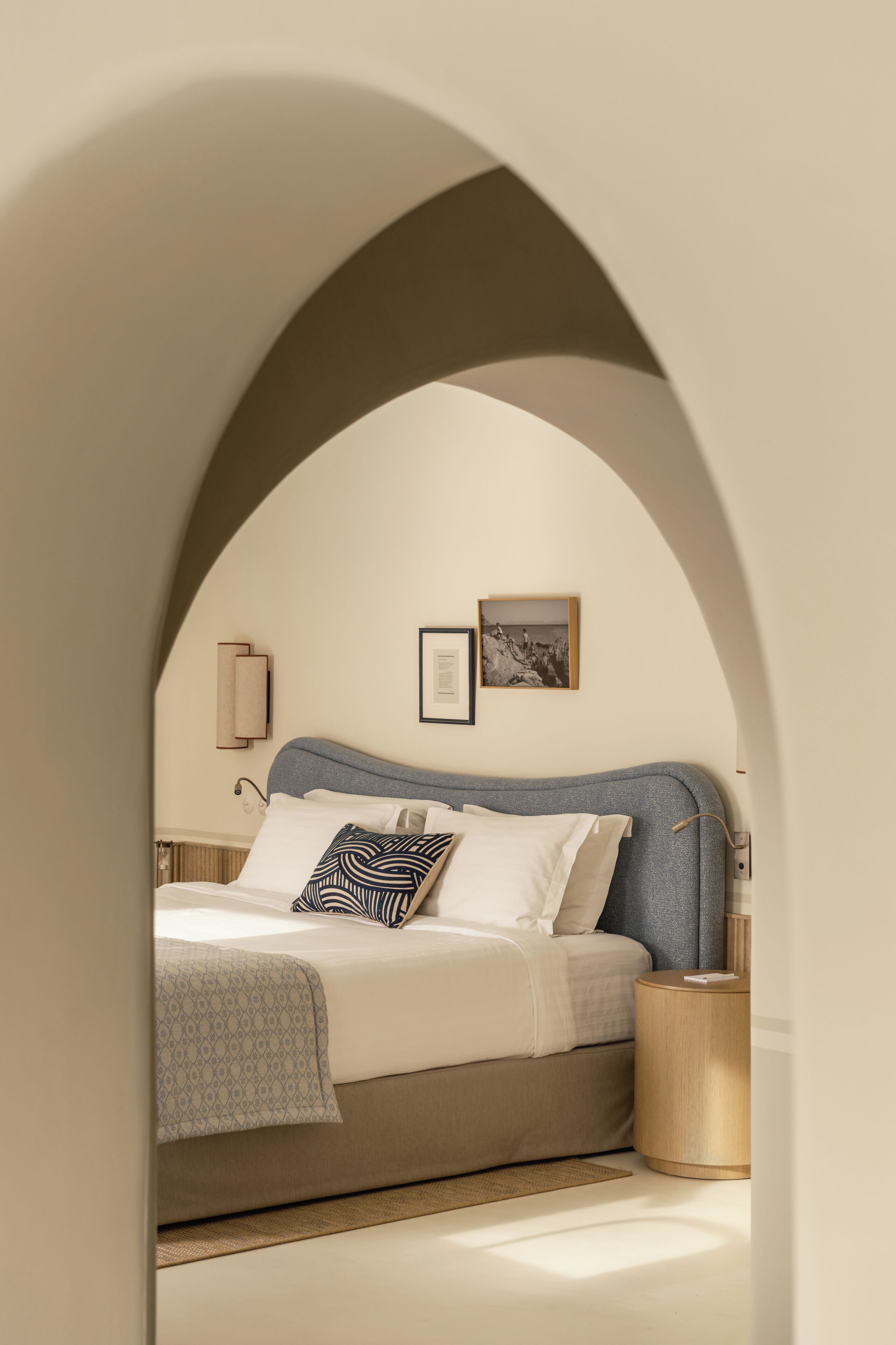 A bedroom with a bed, a bedside table, a lamp, and a framed picture on the wall.