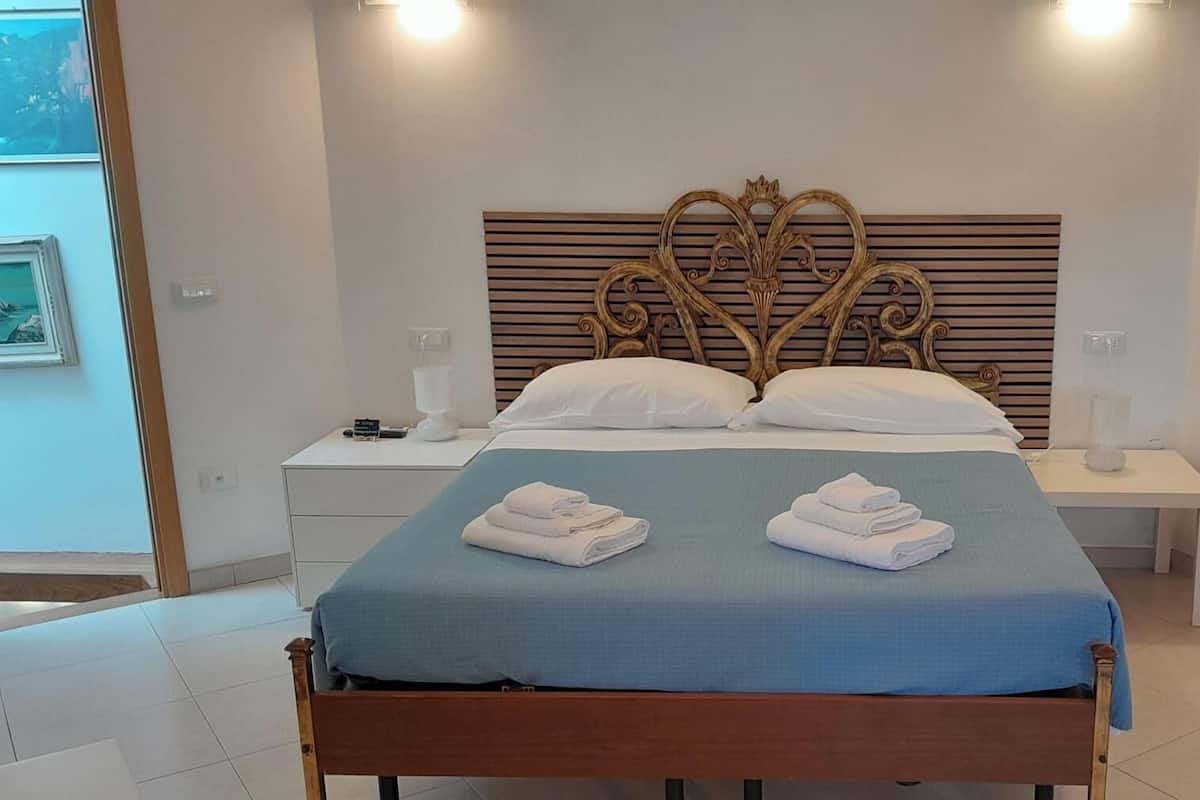 Een hotelkamer met een bed, twee nachtkastjes, een hoofdbord en een badkamer zichtbaar door een geopende deur.