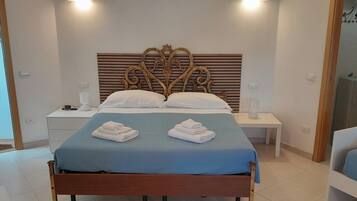 A hotel room with a bed, two bedside tables, a nightstand, a headboard, and a bathroom visible through an open door.