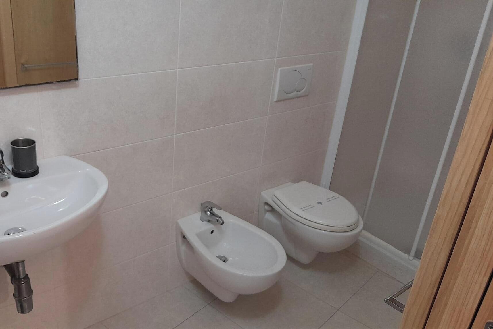 Un baño con lavamanos, bidé, inodoro y espejo.