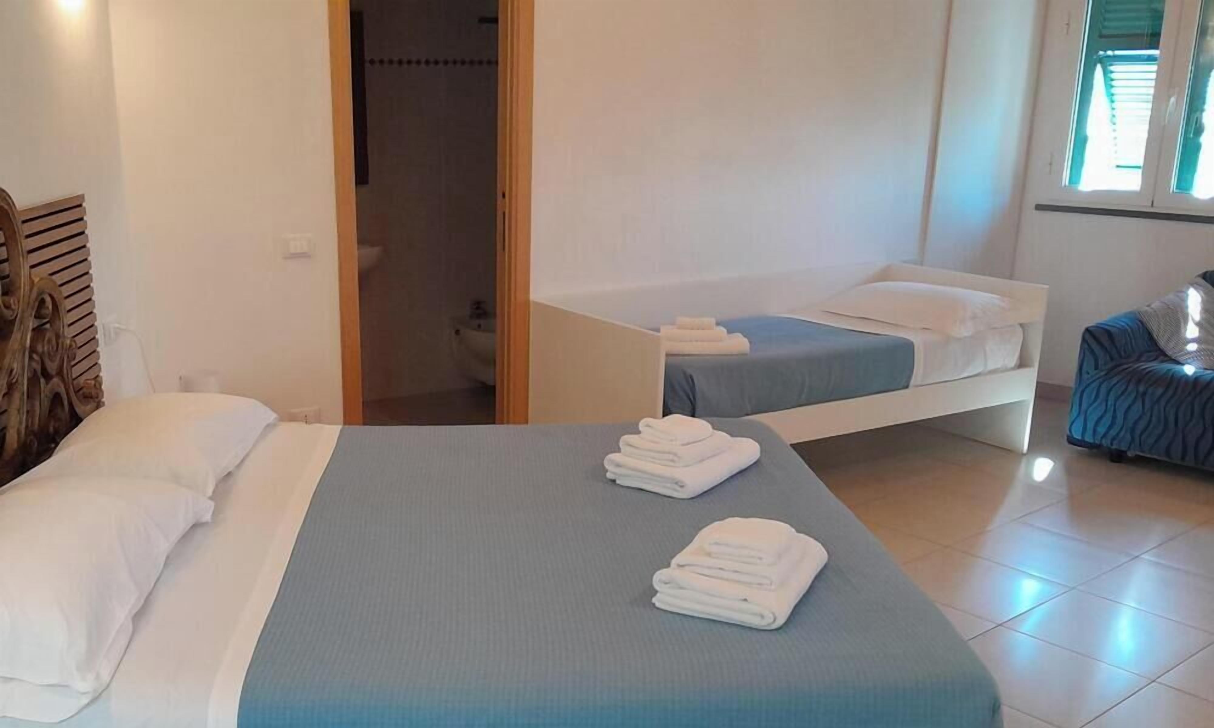 A hotel room with two beds, a bathroom, and a view of the outside.