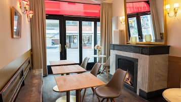 Un hall de hotel con mesas y sillas de madera, una chimenea y un espejo grande.