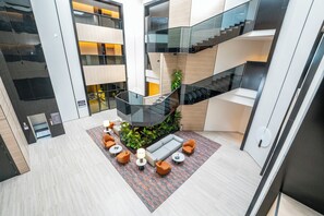 A modern interior with a central seating area, glass railings, and a staircase. - Manazel Al Diafah Serviced Apartment (Riyadh)