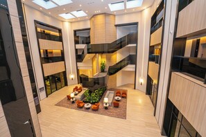 A modern interior with a central staircase, multiple floors, and a seating area with tables and chairs. - Manazel Al Diafah Serviced Apartment (Riyadh)