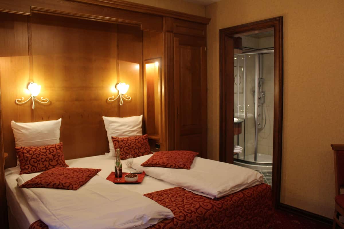 Ein Hotelzimmer mit einem großen Bett, zwei Nachttischen, einem Beistelltisch und einem durch eine offene Tür einsehbaren Badezimmer.