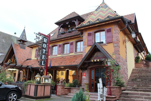 Un hôtel européen traditionnel, reconnaissable à son enseigne bien visible, à sa façade en briques et à son toit à forte pente.