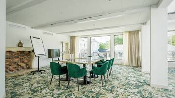 A conference room with a brick fireplace, a whiteboard, and a large window overlooking a building.
