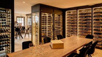 A wine cellar with rows of wine bottles and a long table with wine glasses.