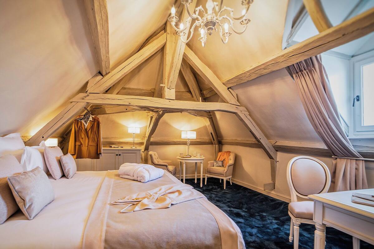 A cozy attic bedroom with a bed, a desk, and a chair.