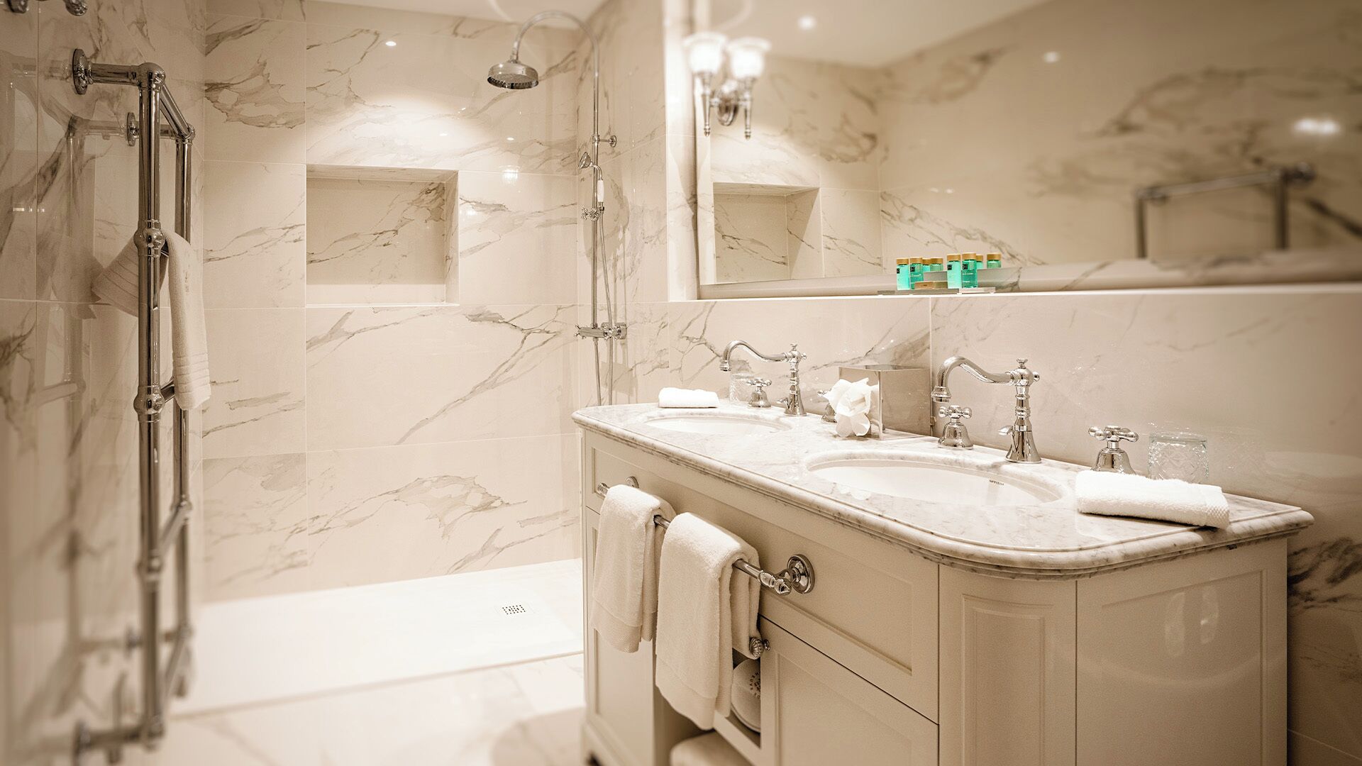 Une salle de bain dotée d’une douche à parois de verre, d’un meuble-lavabo à deux vasques et d’un grand miroir.