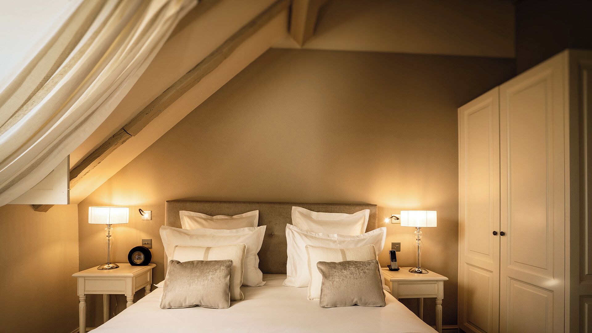 Une chambre d’hôtel avec un grand lit, deux tables de chevet avec des lampes et une armoire.