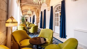Un vestíbulo de hotel con sillas amarillas, una araña y una alfombra azul.