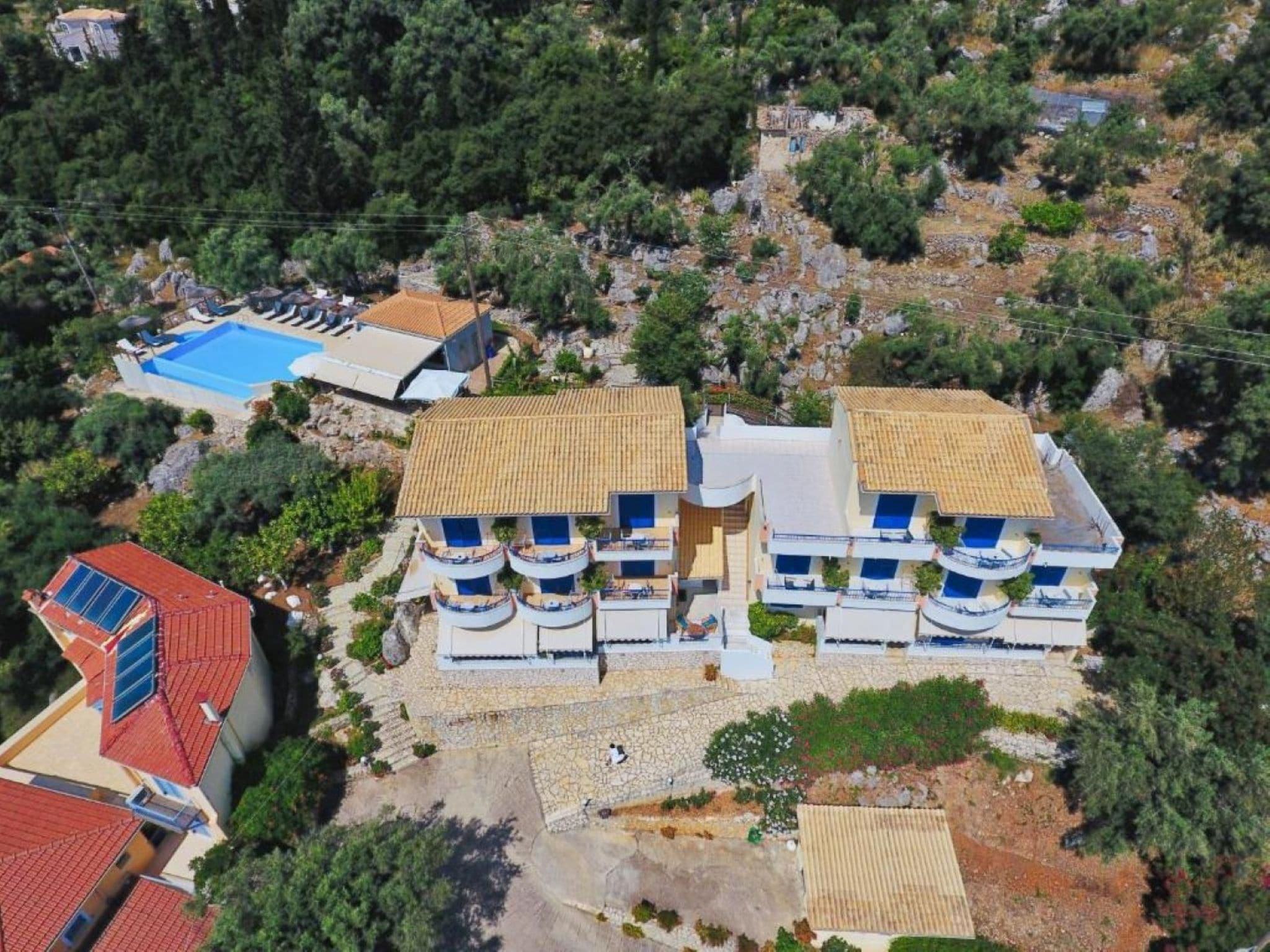 Un edificio de varios pisos con balcones, una piscina y un paisaje rocoso.