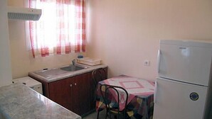 A compact kitchen with a sink, a refrigerator, and a dining table with chairs. - La Casa Di Nonna Anna (Lefkada)