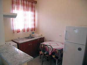 A compact kitchen with a sink, a refrigerator, and a dining table with chairs. - La Casa Di Nonna Anna (Lefkada)