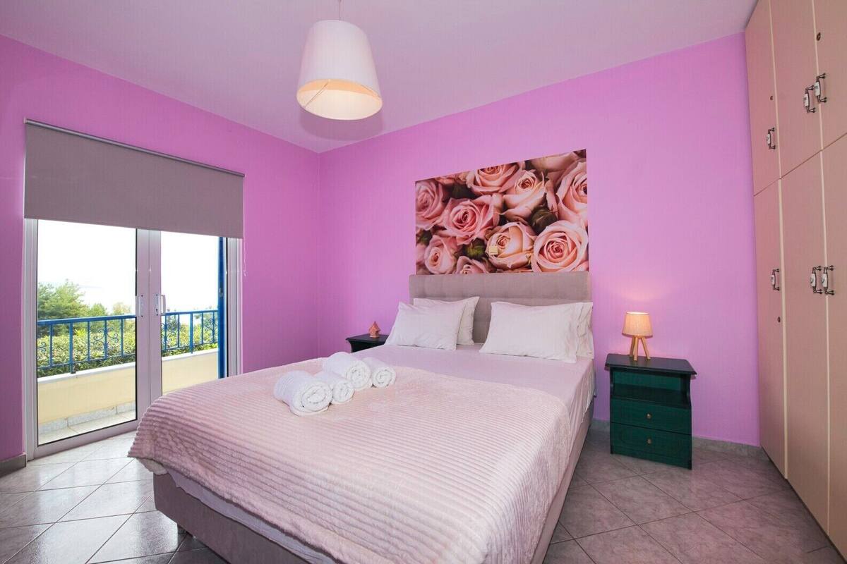 Un dormitorio con cama, mesita de noche, cómoda, ventana grande y balcón.
