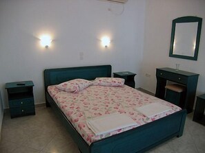 A bedroom with a bed, nightstands, a dresser, and a mirror.
