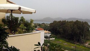 A balcony with a white umbrella, overlooking a coastal landscape with houses and trees. - La Casa Di Nonna Anna (Lefkada)