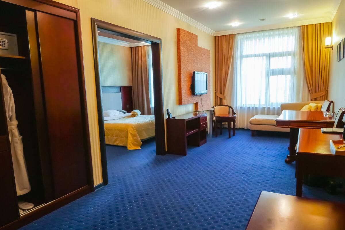 Une chambre d’hôtel comprenant un lit, un bureau, une chaise, une télévision et une armoire.