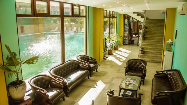 A spacious lobby with leather sofas, a coffee table, and large windows overlooking a swimming pool. - Dubai International Hotel (Baku)