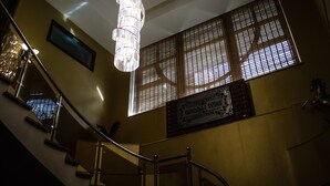 A staircase with a chandelier, a window with a grid pattern, and a sign on the wall. - Dubai International Hotel (Baku)