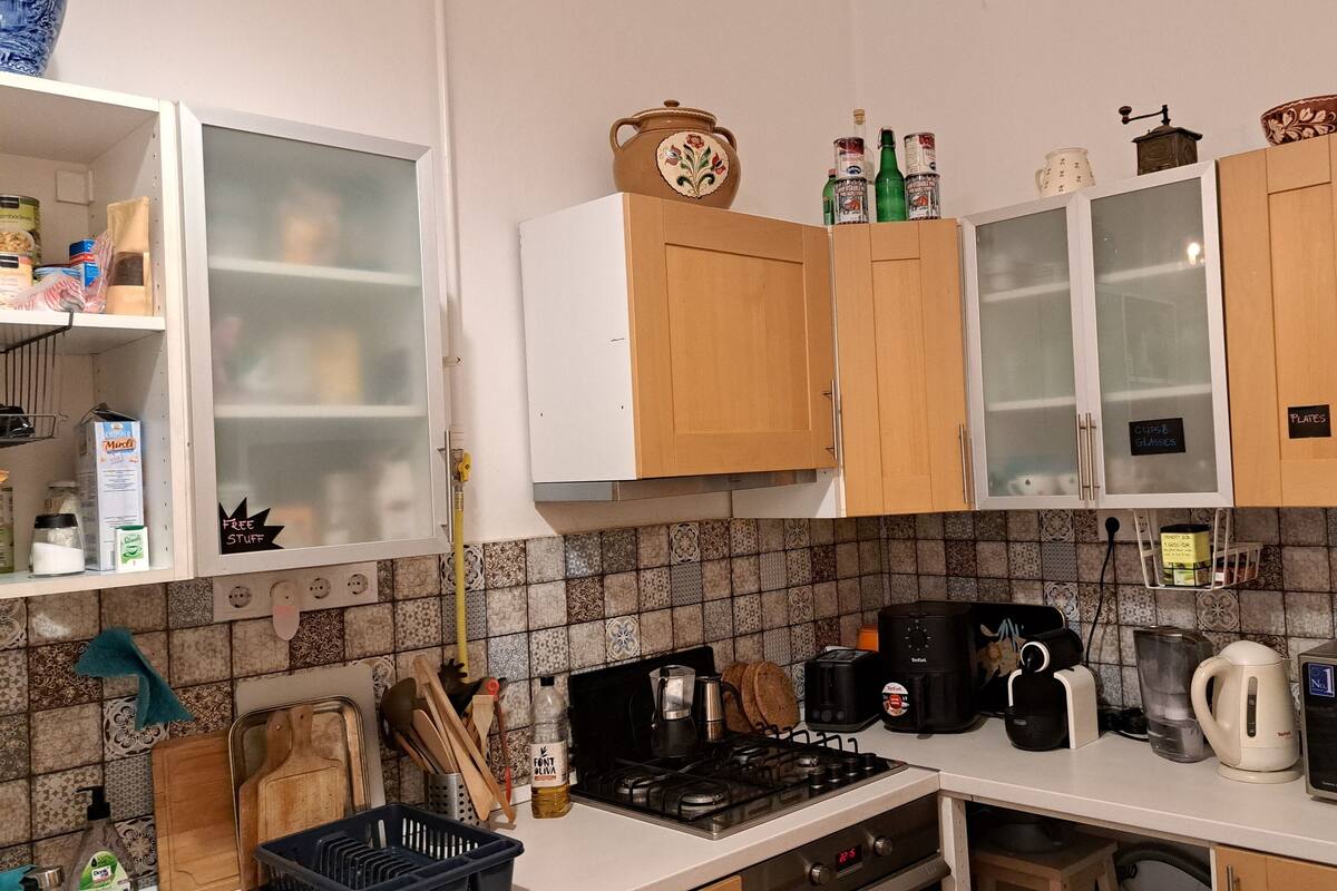 A kitchen with wooden cabinets, a gas stove, a microwave, a toaster, and various kitchen utensils.