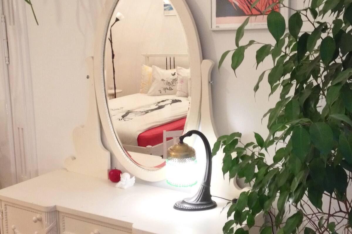 A white vanity with a mirror, a small plant, and a framed picture on the wall.