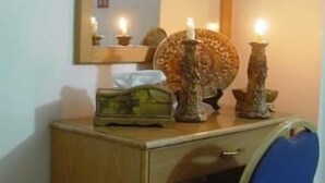 A small wooden desk with a mirror, a blue chair, and three lit candles. - Valentine Inn (Wadi Musa)