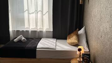 A bedroom with a bed, a bedside lamp, a small table with a candle and a menu, and a fluffy rug.