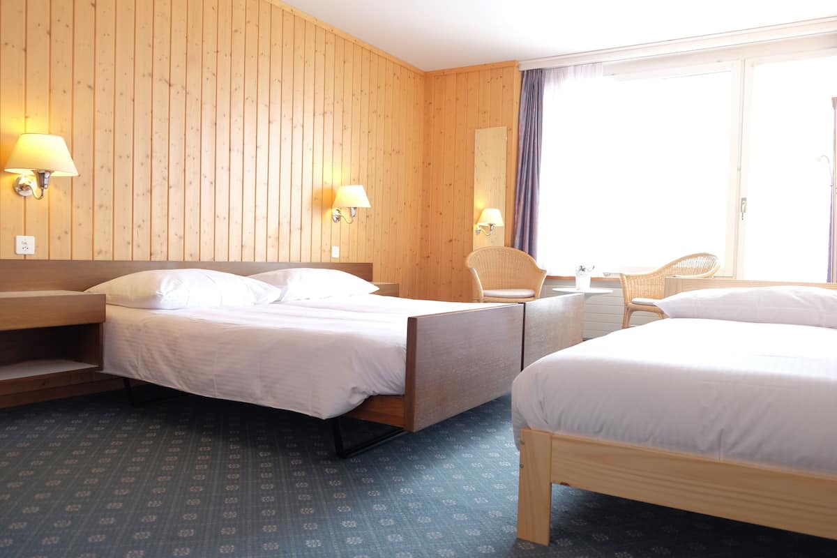 A hotel room with two beds, wooden walls, and a large window.