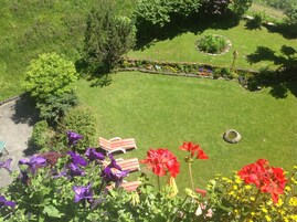 A well-maintained garden with a lawn, a variety of flowers, and a small pond.