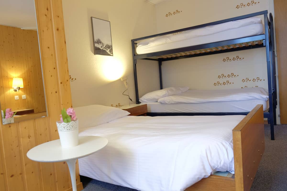 A bunk bed room with a small table and a vase of flowers.