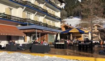 Un hotel con mesas al aire libre y un patio cubierto.