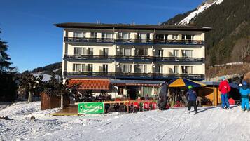 A multi-story hotel with outdoor seating and a ski slope in the background.
