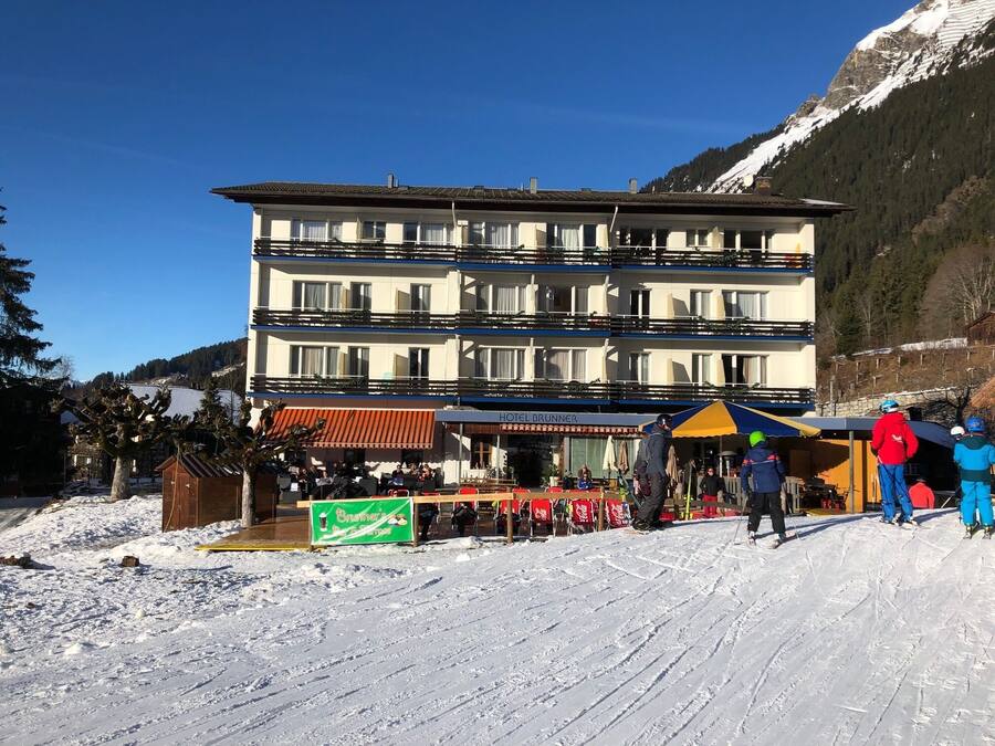 A multi-story hotel with outdoor seating and a ski slope in the background.
