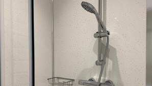 A modern shower with a handheld showerhead and a handheld shower attachment. - Twickenham Guest House (Twickenham)