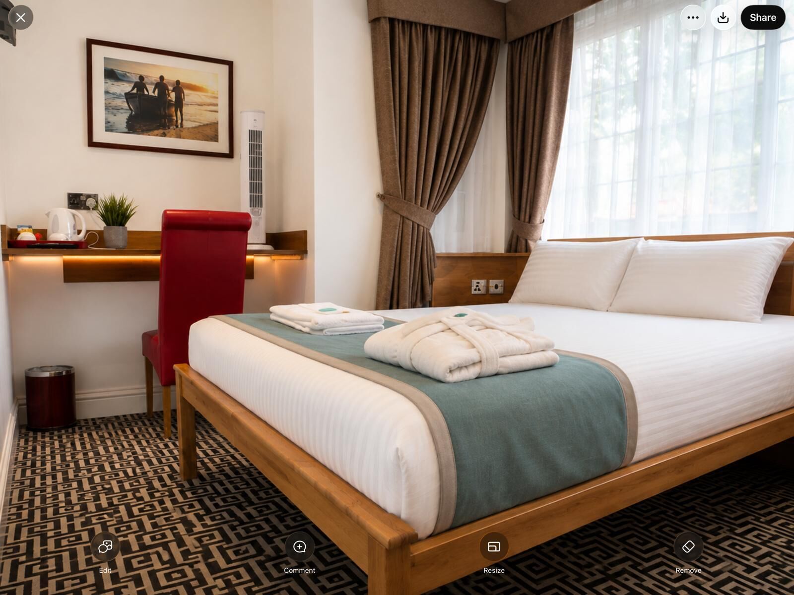 A hotel room with a bed, a desk with a chair, a picture on the wall, and a window with curtains.