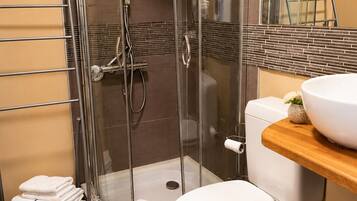 A bathroom with a glass-enclosed shower, a toilet, a sink, and a towel rack.