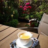 A wooden table with a cup of coffee on a saucer.
