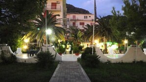 A pathway leading to a building with balconies, surrounded by greenery and street lamps. - Hotel Mondial (Praia a Mare)