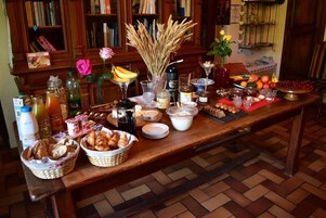 Un bufé de desayuno con diversos alimentos, bebidas y elementos decorativos como flores y espigas de trigo.