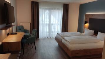 Une chambre d’hôtel équipée d’un lit, d’un bureau, d’une chaise, d’une télévision et d’une fenêtre avec des rideaux.